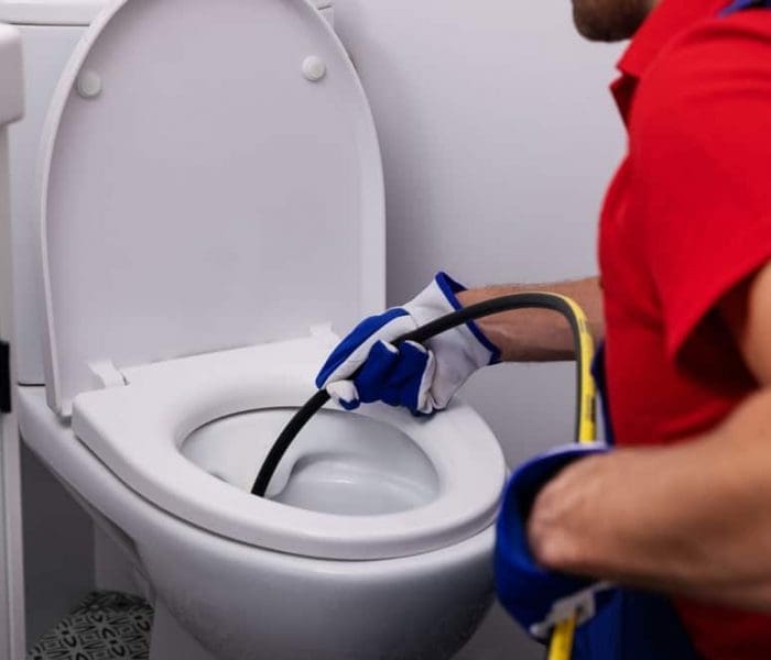 plumber unclogging toilet